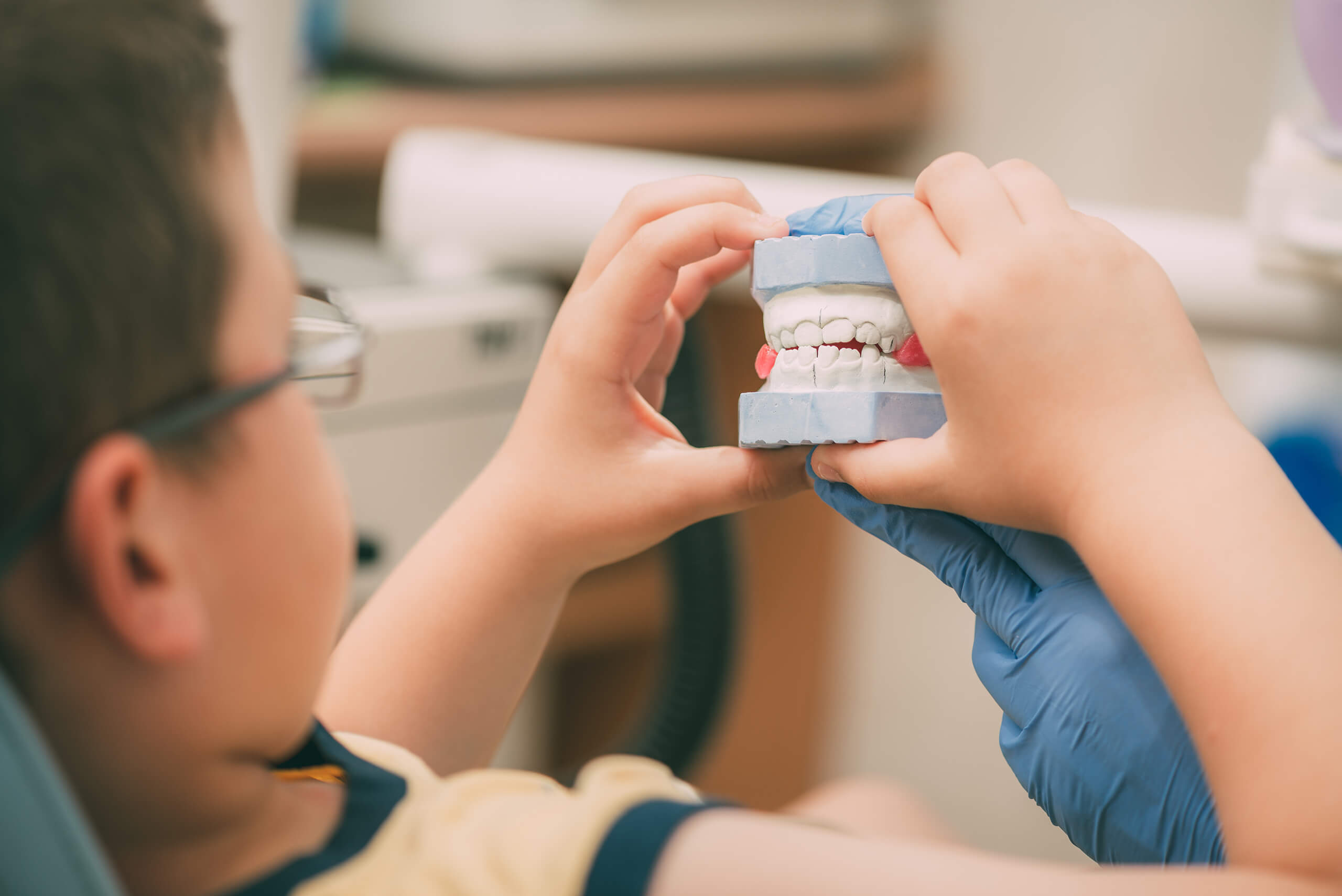 A child in a dentist's chair looks at tooth impressions.